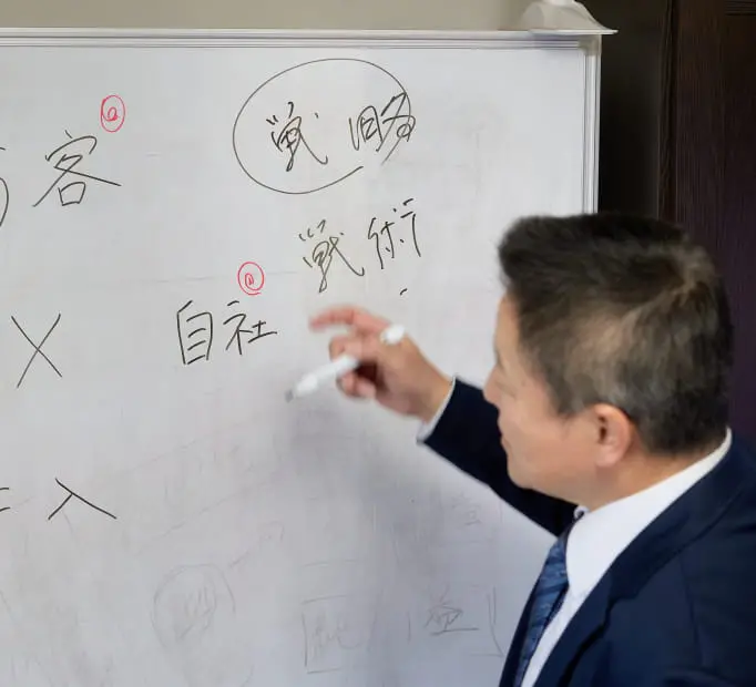 ホワイトボードに文字を書いているスーツ姿の男性